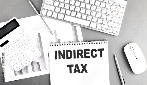Fotografija INDIRECT TAX text written on notebook on grey background with chart and keyboard