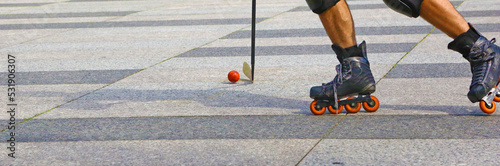 Roller in-line hockey outdoor. Closeup of two legs, the stick and the ball.