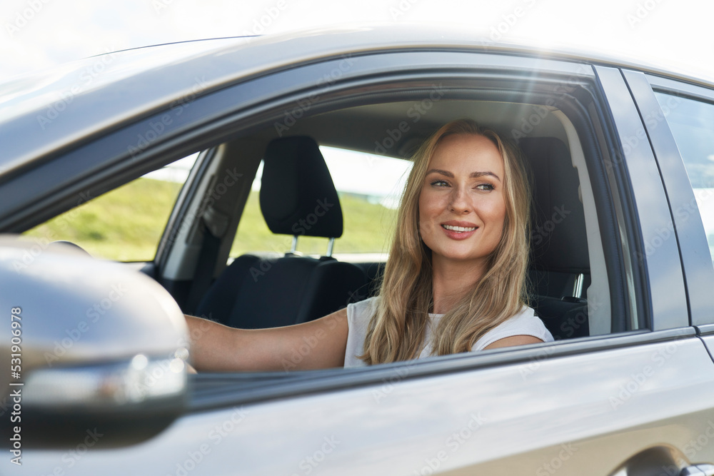 Caucasian adult blonde woman driving a car