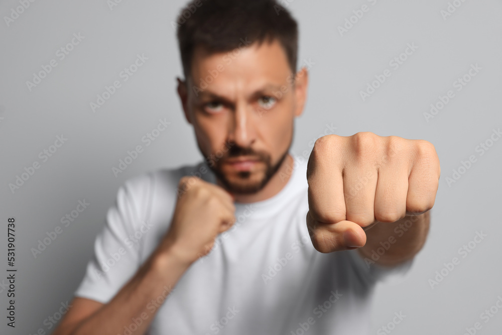 Man throwing punch against grey background, focus on fist. Space for text Man throwing punch against grey background, focus on fist. Space for text