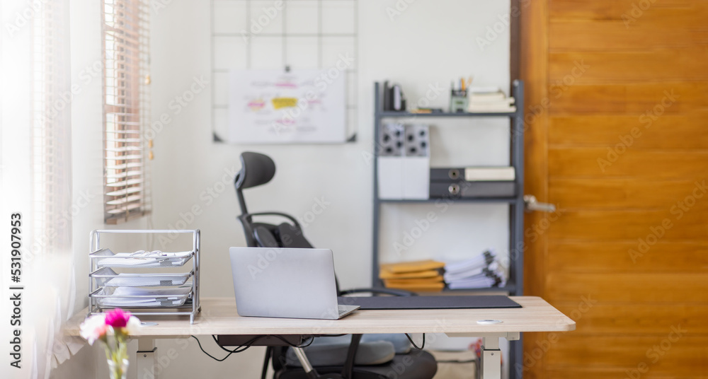 Laptop Computer, notebook, and eyeglasses sitting on a desk in a large open plan office space after working hours Laptop Computer, notebook, and eyeglasses sitting on a desk in a large open plan office space after working hours