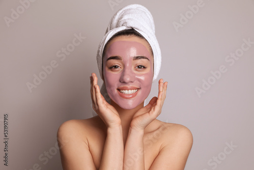 Woman with pomegranate face mask on grey background