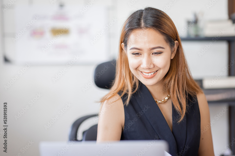 Young Asian female freelancer employee working at home workplace with laptop and papers on desk Young Asian female freelancer employee working at home workplace with laptop and papers on desk