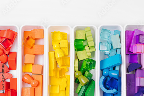 Educational games for Colors sorting. Red, yellow, green and blue wooden blocks in boxes. Colors sorter toy. Learning through play. Developing Montessori toddlers activities.
