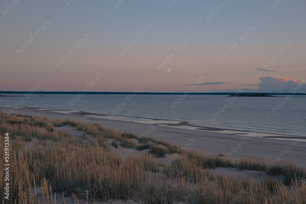 sandbeautiful view of an old wooden pier on the beach dunes on the seashore and the moon in the sky sandbeautiful view of an old wooden pier on the beach dunes on the seashore and the moon in the sky