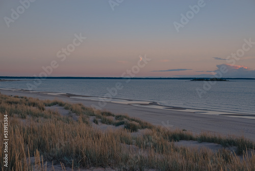 Fototapeta Naklejka Na Ścianę i Meble -  sandbeautiful view of an old wooden pier on the beach dunes on the seashore and the moon in the sky