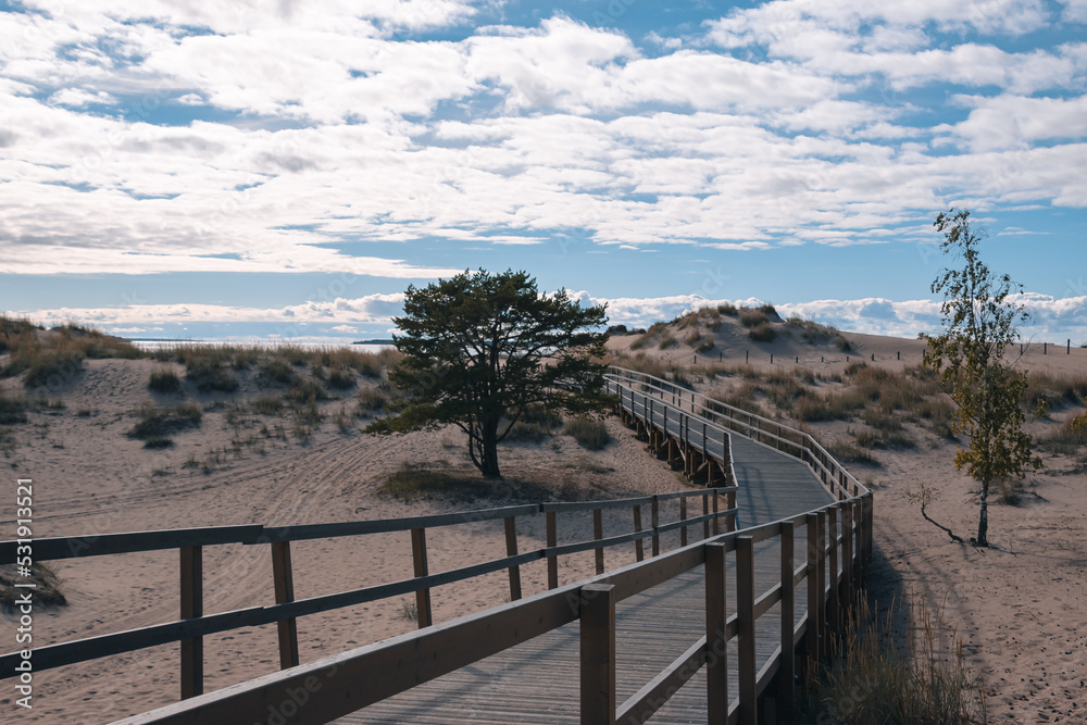 wooden path in sand dunes against a cloudy sky wooden path in sand dunes against a cloudy sky