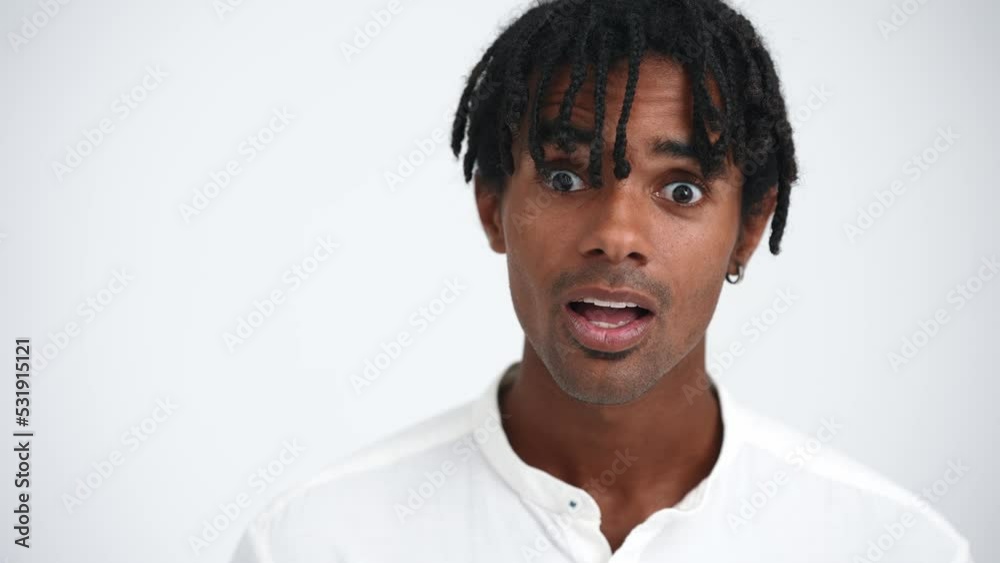 Face of surprised African man with dreadlocks looking at camera in the white studio Face of surprised African man with dreadlocks looking at camera in the white studio