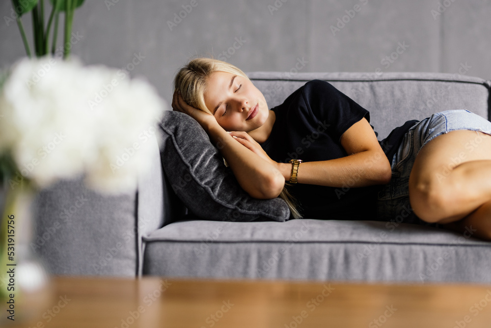Obraz premium Young attractive woman sleeping on the couch in the living room