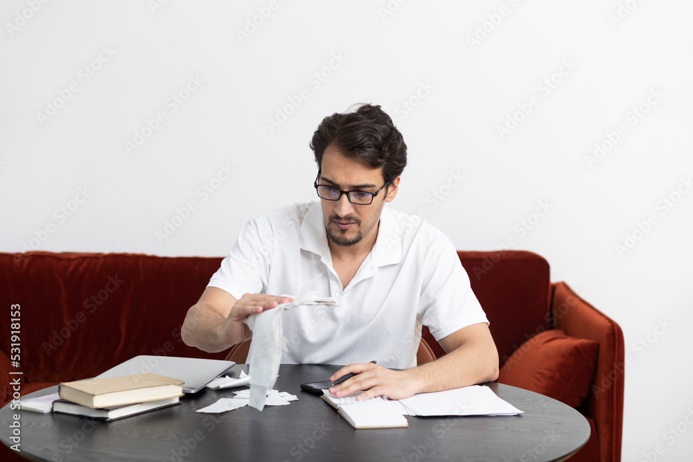 Close up of unhappy man sitting at the table, stressed and confused by calculate expense from invoice or bills, have no money to pay mortgage or loan. High prices and spending money concept Close up of unhappy man sitting at the table, stressed and confused by calculate expense from invoice or bills, have no money to pay mortgage or loan. High prices and spending money concept
