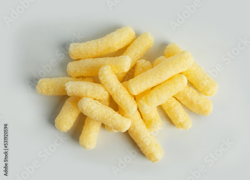 Pile of delicious crispy corn sticks on white background, flat lay