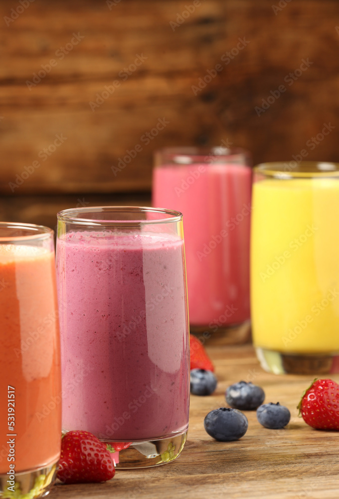 Glasses with different tasty smoothies on wooden table Glasses with different tasty smoothies on wooden table
