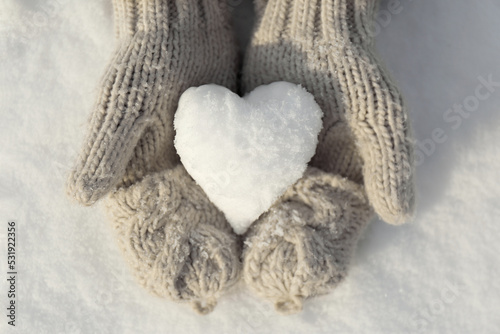 Woman holding heart shaped snowball outdoors, top view
