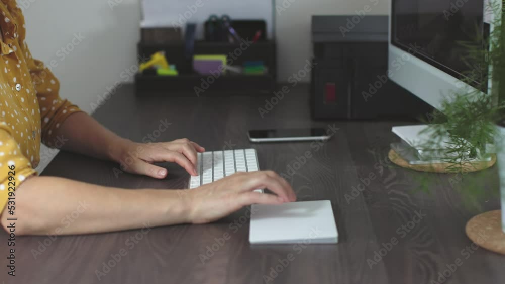 female hands in yellow dress using white touchpad keyboard surfing internet website computer monitor home desk workplace concept. woman sitting table work home office distant. fingers touching pad