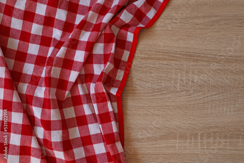 Checkered picnic cloth on wooden table, top view. Space for text