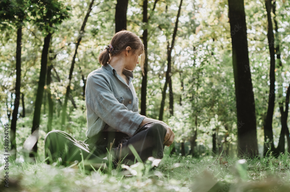 Woman doing a seated twist with forest background Woman doing a seated twist with forest background