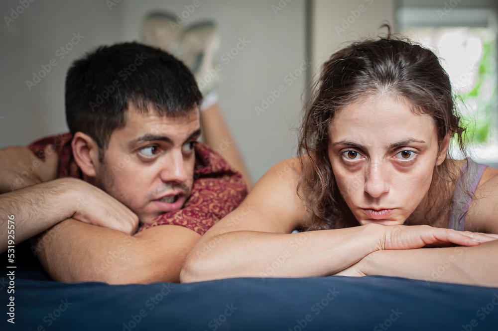 Obraz premium A man and a woman are arguing on the bed in the apartment. They are in a bad mood because they have love problems.