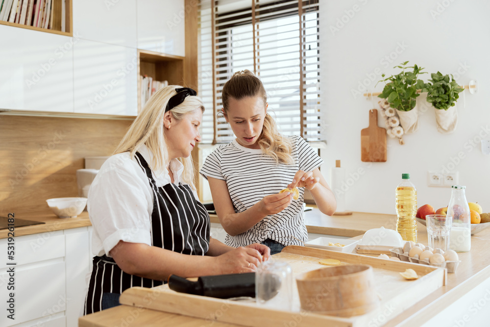 Delighted young daughter spending time with elderly mother making varennyky talking. Happy women cooking preparing family dinner. Delighted young daughter spending time with elderly mother making varennyky talking. Happy women cooking preparing family dinner.