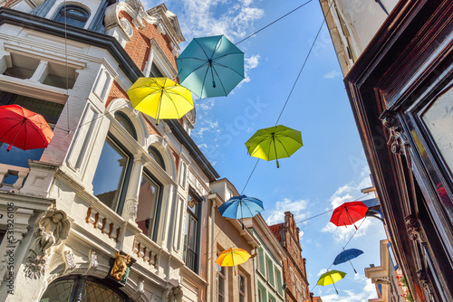Colorful umbrellas in the air against blue sky with clouds photo