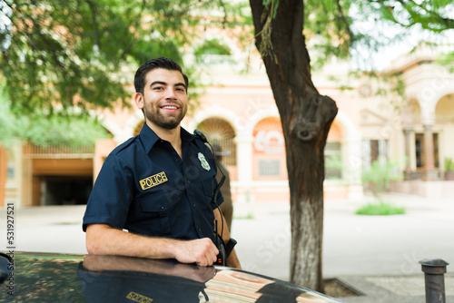 Portrait of a happy male cop leaning into the police car