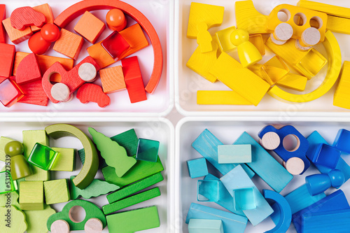 Educational games for Colors sorting. Red, yellow, green and blue wooden blocks in boxes. Colors sorter toy. Learning through play. Developing Montessori toddlers activities.