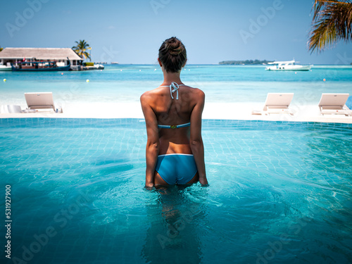 Travel vacation - Beautiful young pretty blonde girl back in bikini on her perfect sport sexy body relax in pool near paradise beach at tropical caribbean maldives beach at sunny day in hotel