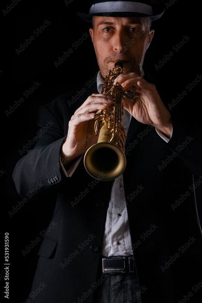 Naklejka premium soprano saxophone in the hands of a guy on a black background