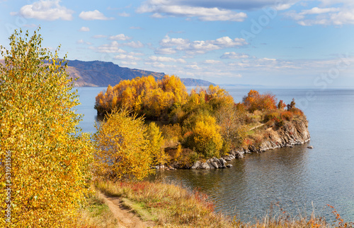Beautiful landscape of Baikal Lake on September sunny day. View from the rocky shore to Cape Shamansky - natural landmark during leaf fall. Autumn nature background. Outdoor recreation and travel
