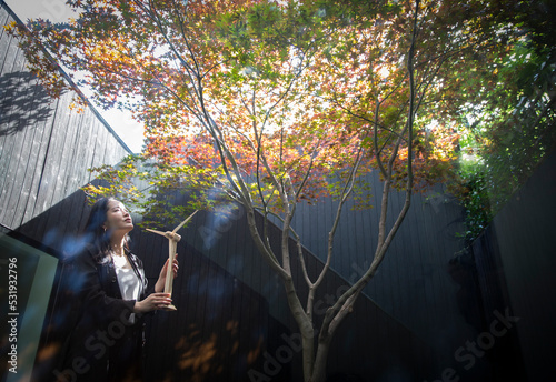 Female engineer with wind turbine model in courtyard with tree