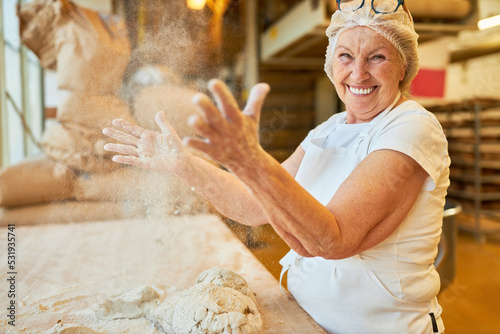 Fototapeta Woman as a baker claps flour from hands in bakery
