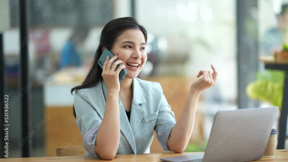 Confident Asian woman sitting talking on the phone in café. Confident Asian woman sitting talking on the phone in café.