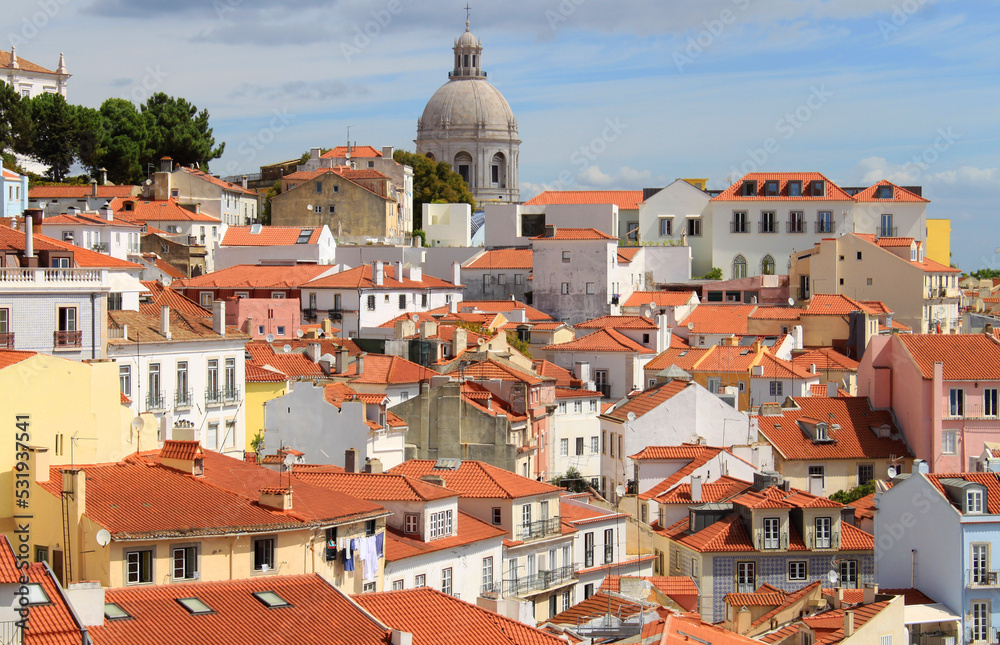Exterior view of beautiful historical buildings, rooftops, and church towers in downtown Lisbon, Portugal Europe. Colorful Mediterranean street with old townhouses in Alfama neighborhood.