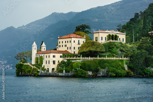 View from water to picturesque Villa Balbianello in Lenno, on Lake Como, Italy, famous place used in Star Wars movie, beautiful landscape with mansion, garden, terrace and mountain in the background