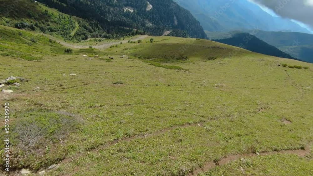 Flight over the top of the hill. The ground is covered with green grass. Mountain landscape. FPV Drone video 4k footage Flight over the top of the hill. The ground is covered with green grass. Mountain landscape. FPV Drone video 4k footage