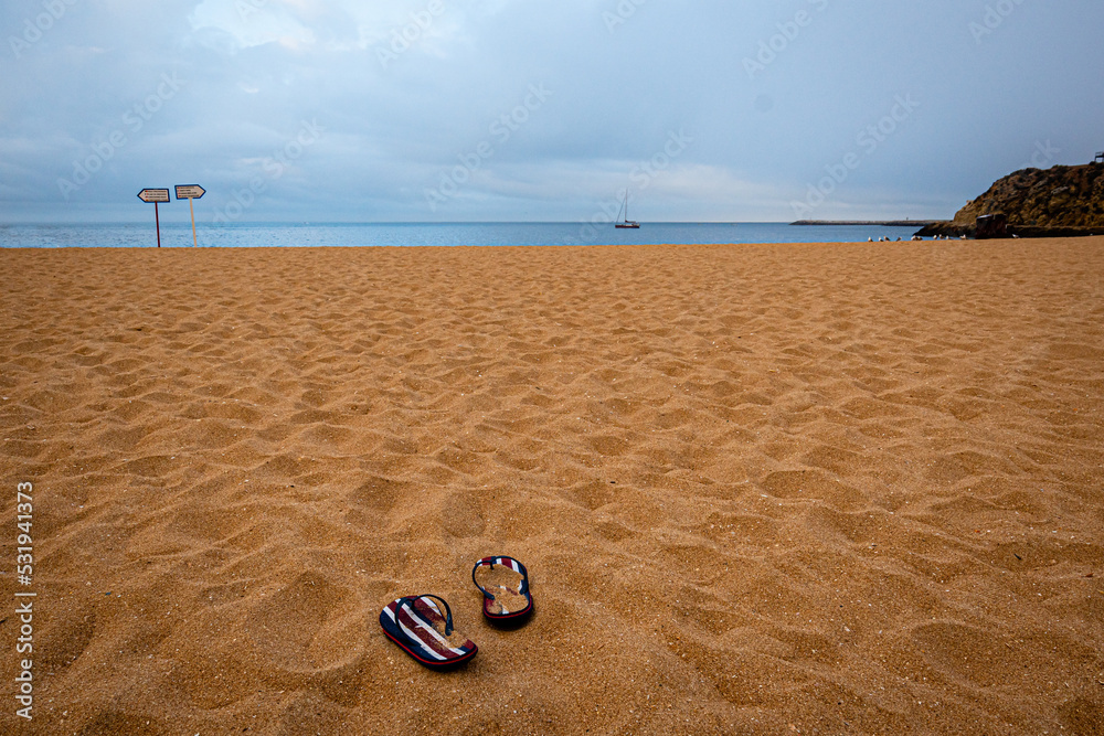 Abufara beach in the moring with striped flip flops and sail boat Abufara beach in the moring with striped flip flops and sail boat
