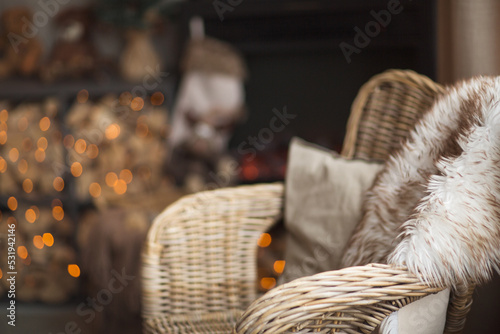 beautiful cozy christmas interior of a country house in the holidays. background with wicker chair, fireplace, firewood