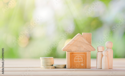 House and coins  placed on the table with happy wooden doll family placed on nature bokeh. planning savings money of coins to buy a home, concept for property, mortgage and real estate investment.