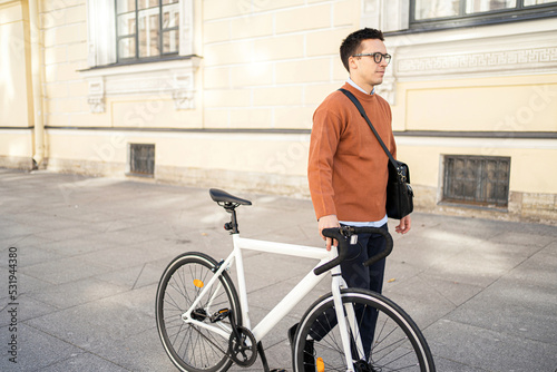 Fototapeta Naklejka Na Ścianę i Meble -  A male cyclist goes to work with a briefcase. Urban ecotransport.