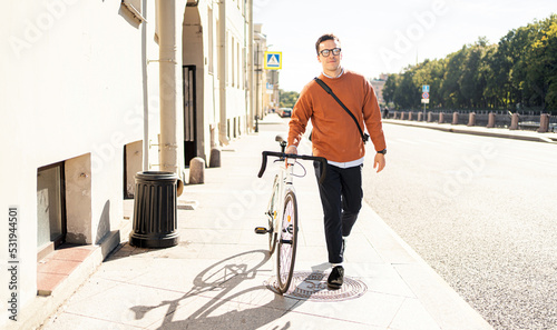 A cyclist goes to work with a briefcase. Urban ecotransport.  Fitness watch on hand. © muse studio