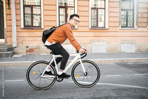 Fototapeta Naklejka Na Ścianę i Meble -  A male cyclist goes to work with a briefcase. Urban ecotransport.