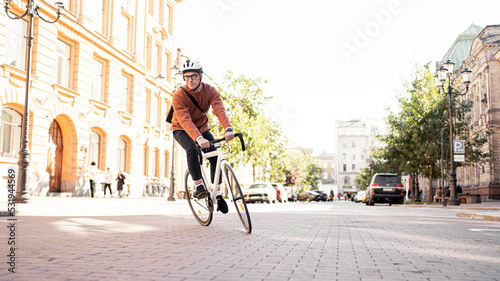 A cyclist in a helmet goes to work with a briefcase. Urban ecotransport. Fitness watch on hand.