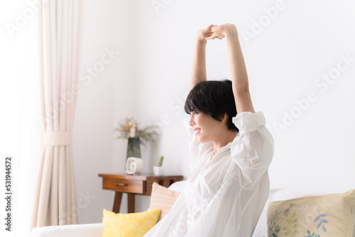 Woman stretching comfortably in her room, profile