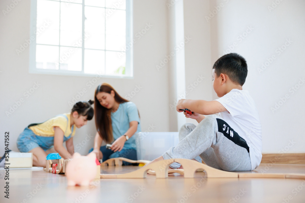 Cute asian boy playing wood block building rail way and road on the floor and his mother and sister help him to do that at home. Cute asian boy playing wood block building rail way and road on the floor and his mother and sister help him to do that at home.