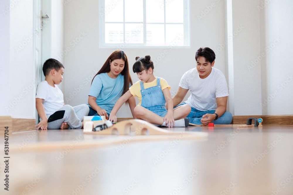 Happy asian family playing wood block create rail road together at home Happy asian family playing wood block create rail road together at home