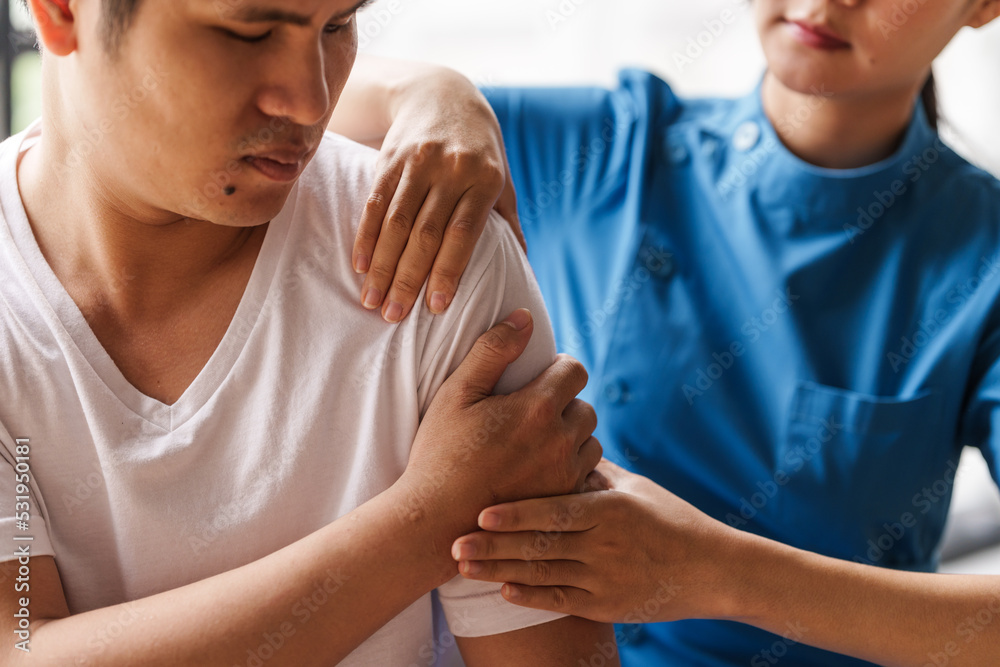 Physical therapist is examining the injured arm, waist and neck muscles of an athletic male patient. Physical therapist is examining the injured arm, waist and neck muscles of an athletic male patient.