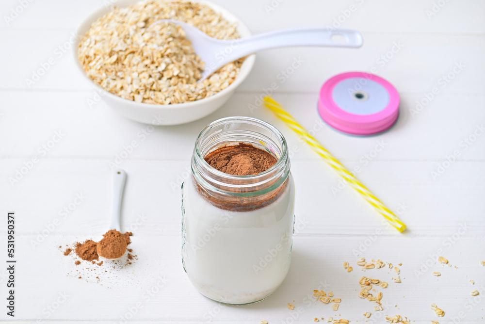 Fototapeta premium Morning healthy breakfast. Cocoa milk and oatmeal granules. Wooden white background.
