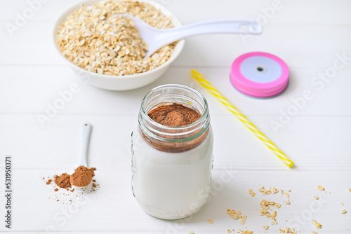 Morning healthy breakfast. Cocoa milk and oatmeal granules. Wooden white background.