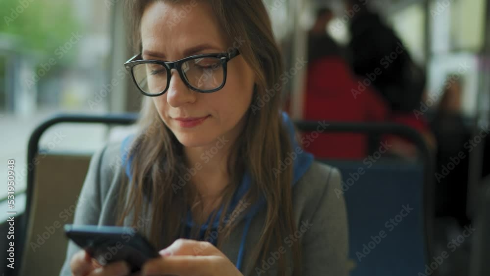 Woman in tram using smartphone chatting and texting with friends.