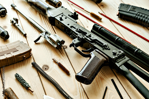 Disassembled rifle with cleaning tools on table of weapons workshop