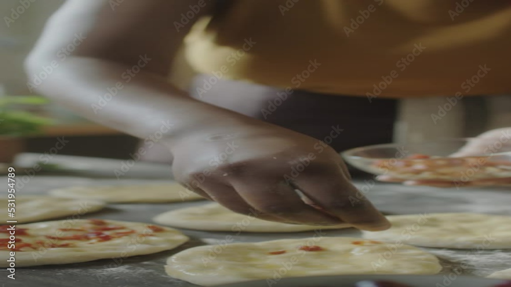Vertical close up shot of hands of unrecognizable woman sprinkling topping on flattened dough pieces before baking buns Vertical close up shot of hands of unrecognizable woman sprinkling topping on flattened dough pieces before baking buns
